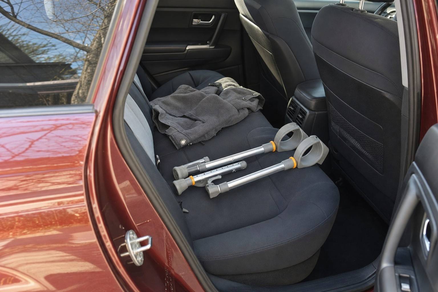 A pair of folded aluminum crutches lying on the back seat of a car